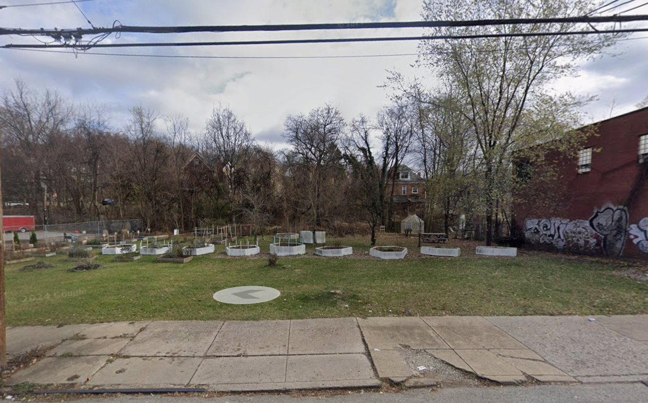 Street-facing view of the existing Helpful Hands Harvest garden site with raised beds